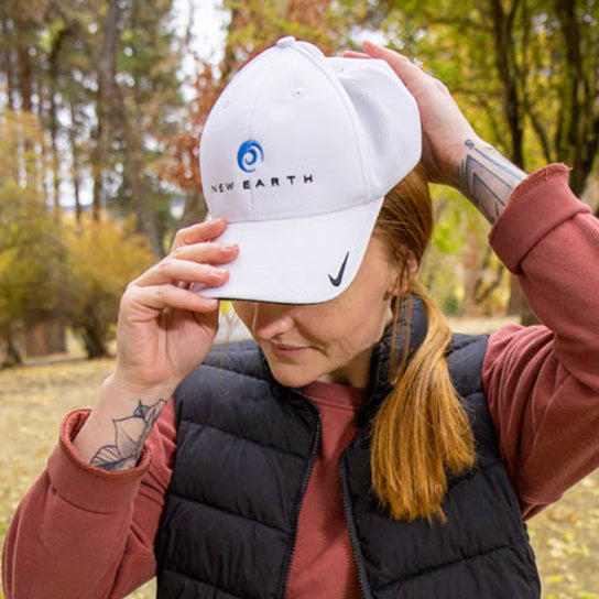 Woman placing a white New Earth hat on her head.