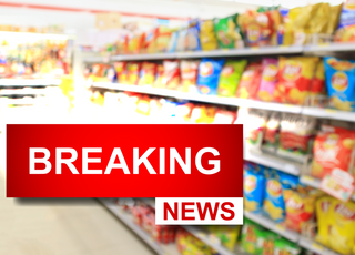 View of the chip aisle of a grocery store with a breaking news icon overlayed over top it.