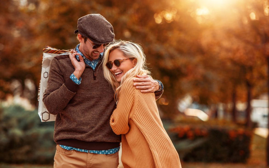 Young couple smiling and hugging while on an autumn walk.