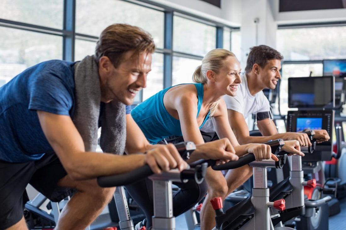 Three people working out on stationary bikes at the gym. 