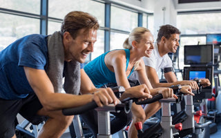 Three people working out on stationary bikes at the gym. 