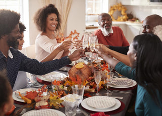 Family sitting around the dinner table clinking glasses.