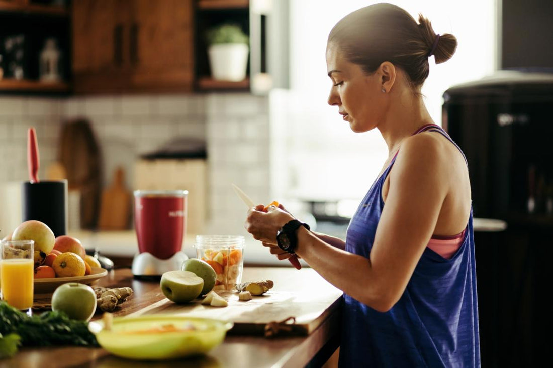 Woman standing at a kitchen counter preparing ingredients for a smoothie.