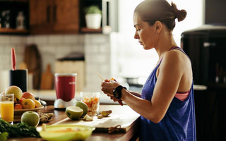 Woman standing at a kitchen counter preparing ingredients for a smoothie.