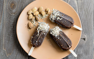 Three fudgesicles topped with coconut shavings sitting on a light brown plate.