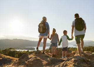 Family of four holding hands and enjoying the view from the top of the hill they just hiked.