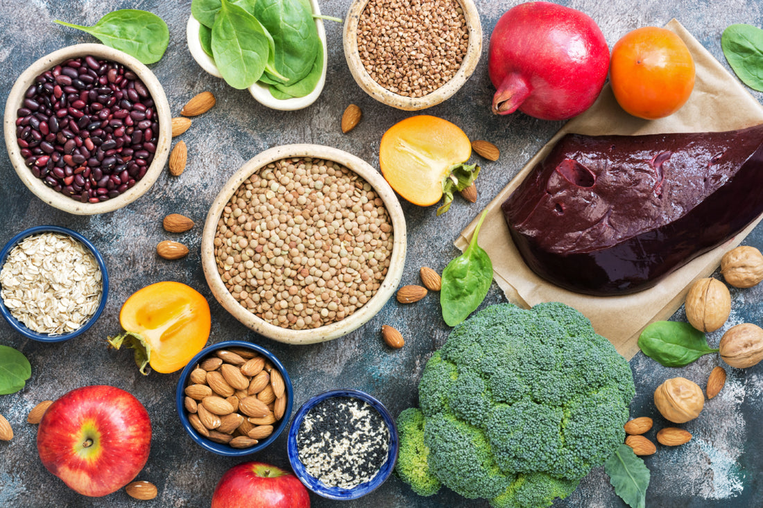 Top-down view of a grey counter full of mineral-rich foods like seeds, vegetables, and nuts. 