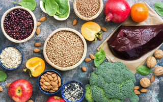 Top-down view of a grey counter full of mineral-rich foods like seeds, vegetables, and nuts. 