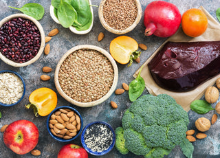 Top-down view of a grey counter full of mineral-rich foods like seeds, vegetables, and nuts. 