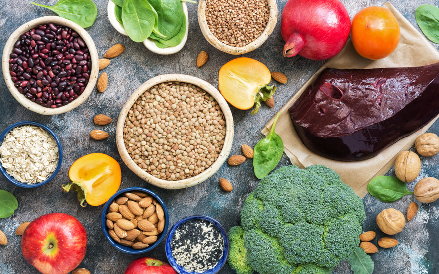 Top-down view of a grey counter full of mineral-rich foods like seeds, vegetables, and nuts. 