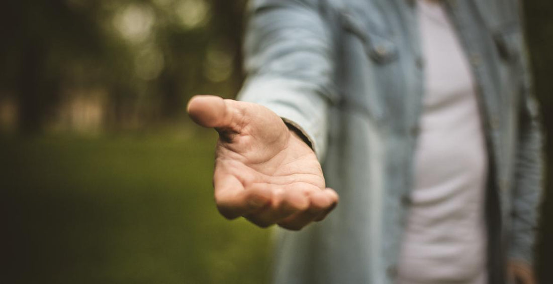 Person reaching their hand toward the camera as if offering assistance.