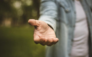 Person reaching their hand toward the camera as if offering assistance.