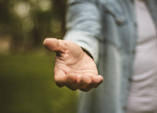 Person reaching their hand toward the camera as if offering assistance.