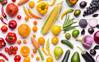 A table full of fresh fruits and vegetables arranged according to color.