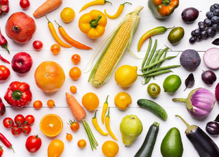 A table full of fresh fruits and vegetables arranged according to color.