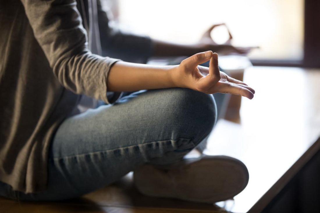 Close up of woman sitting cross-legged on the ground to meditate. 