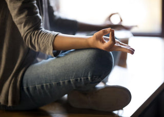 Close up of woman sitting cross-legged on the ground to meditate. 