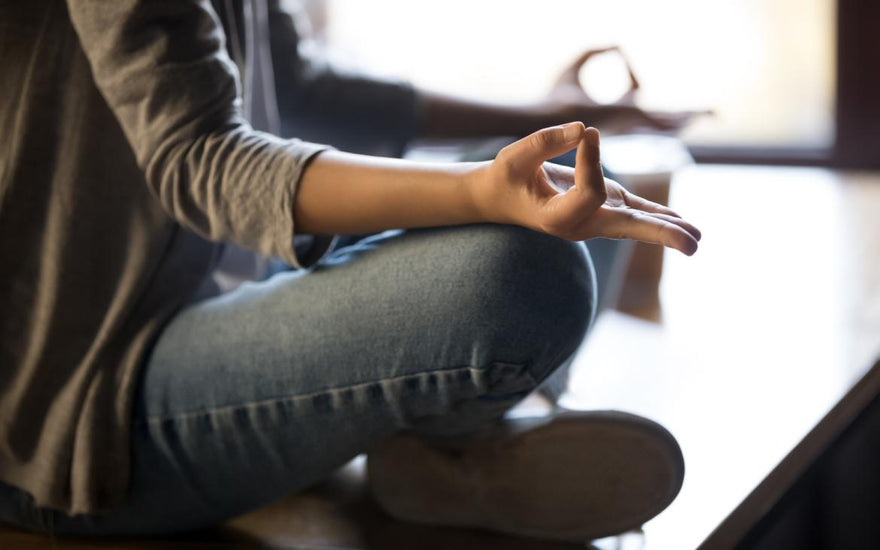 Close up of woman sitting cross-legged on the ground to meditate. 