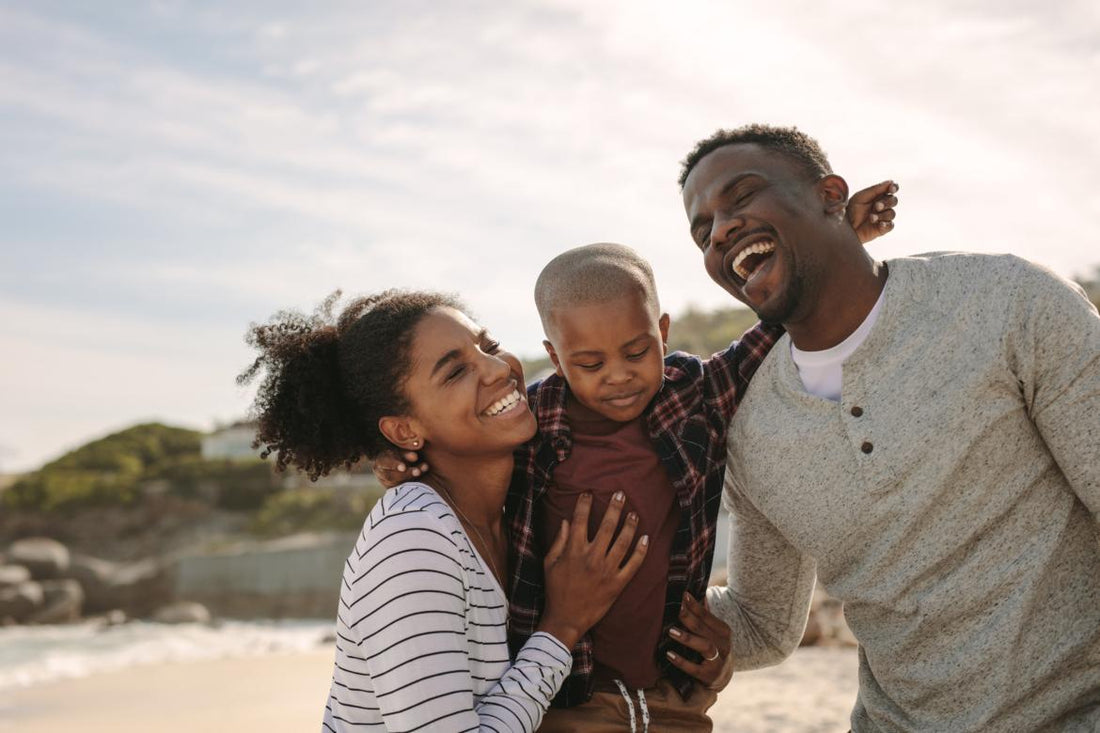Family of three smiling and laughing while hugging each other outside.