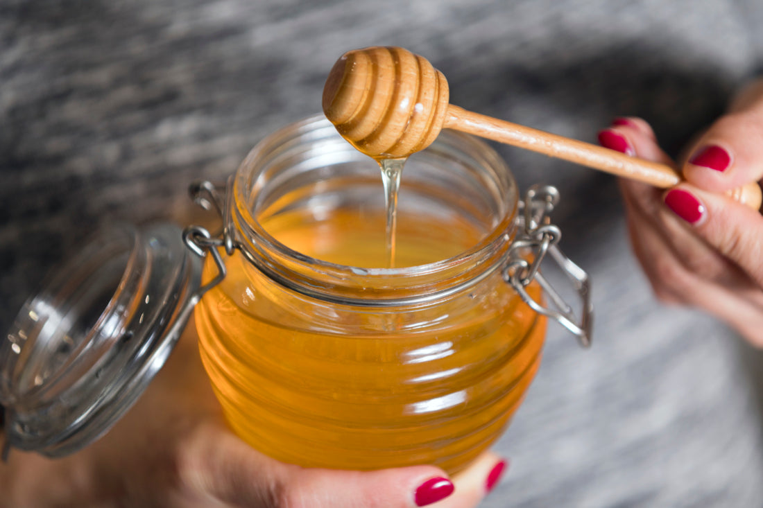 Person holding an open jar of honey.