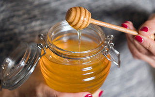 Person holding an open jar of honey.