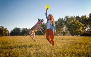 Woman playing frisbee with her dog in an open field.