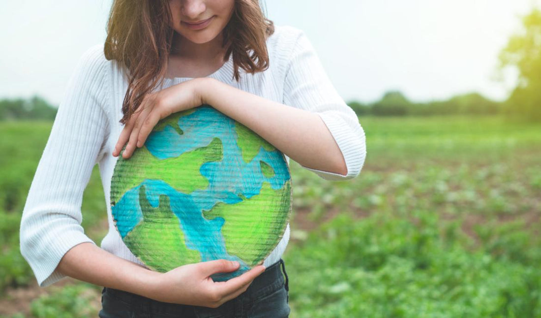 Young woman holding a round piece of cardboard colored to look like the Earth.