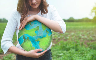 Young woman holding a round piece of cardboard colored to look like the Earth.