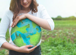 Young woman holding a round piece of cardboard colored to look like the Earth.