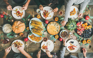 Top down view of a holiday dinner table as people reach to serve themselves food.