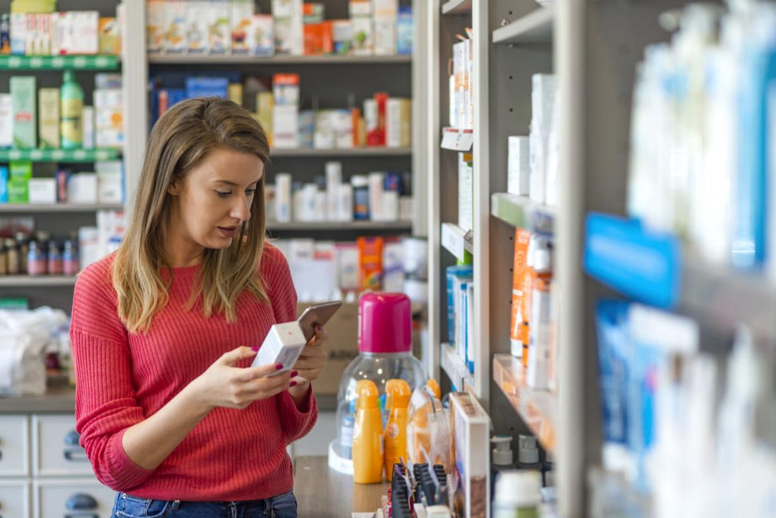 Young women in a red shirt standing in a supplement aisle reading the back of a product. 