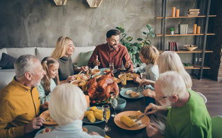 Multi-generational family sitting around a table enjoying a holiday meal.