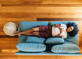 Top down view of a woman laying on a blue couch, relaxing while looking at her phone. 