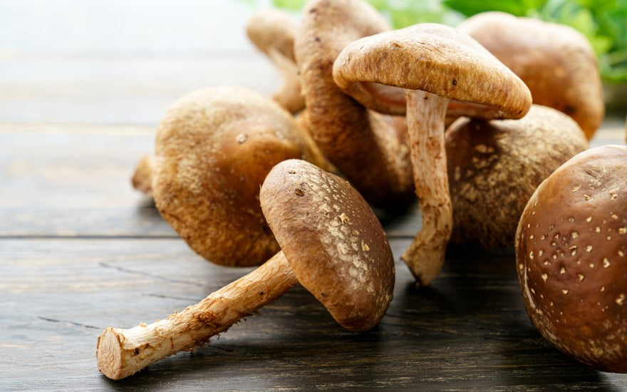 A small pile of mushrooms laying on a wooden tabletop. 