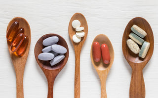 Five wooden spoons of various sizes each holding a two to five of a different type of pill.