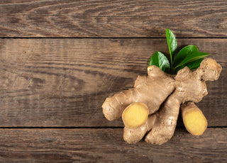 A fresh clump of ginger sitting on a dark wood tabletop.