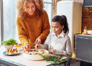 Happy woman and a young girl making healthy vegan food for a family gathering. 