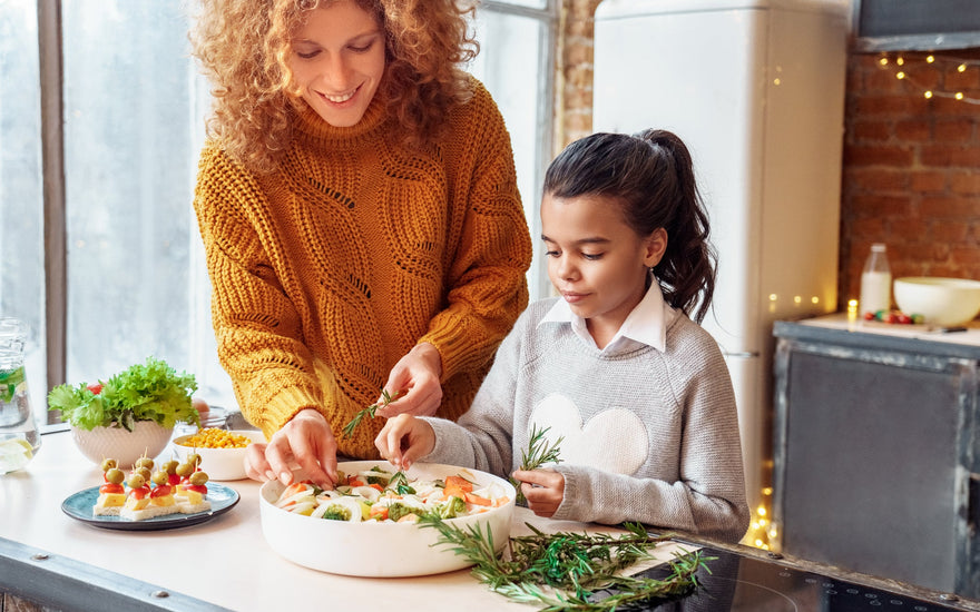 Happy woman and a young girl making healthy vegan food for a family gathering. 