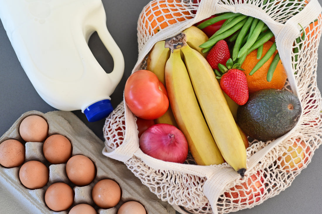Shopping bag full of fresh vegetables and fruits with milk and eggs.