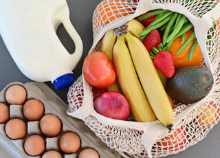 Shopping bag full of fresh vegetables and fruits with milk and eggs.