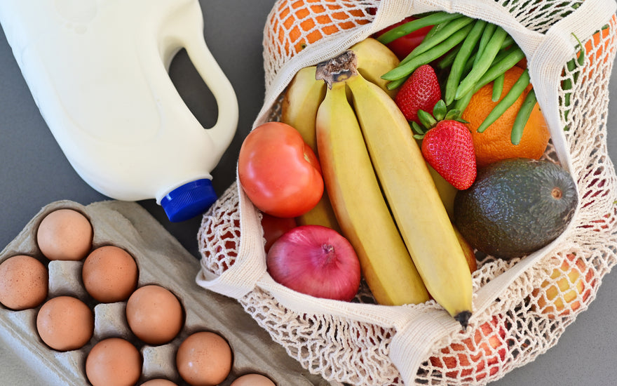 Shopping bag full of fresh vegetables and fruits with milk and eggs.
