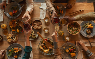 A view from above of a family making a toast over a vegan holiday dinner. 