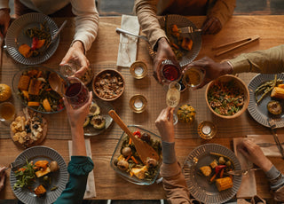 A view from above of a family making a toast over a vegan holiday dinner. 