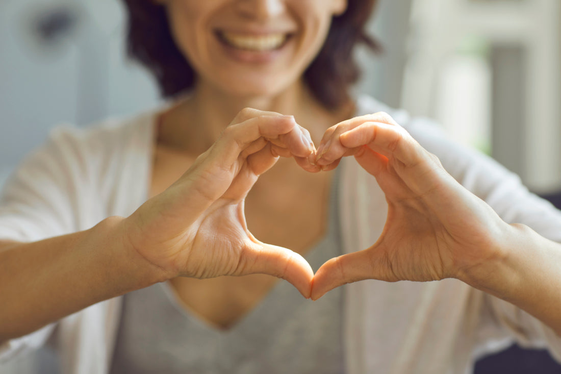 Woman holding her hands in a heart shape out in front of her.