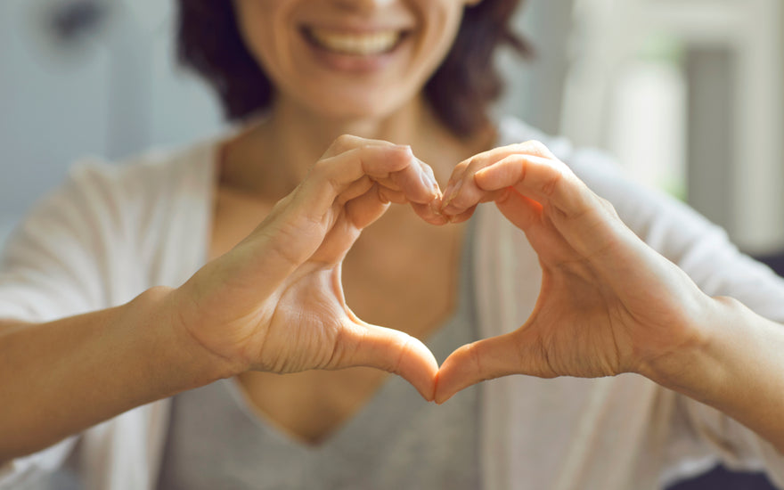 Woman holding her hands in a heart shape out in front of her.