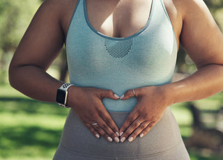 Woman resting with her hands over her stomach after her outdoor workout. 