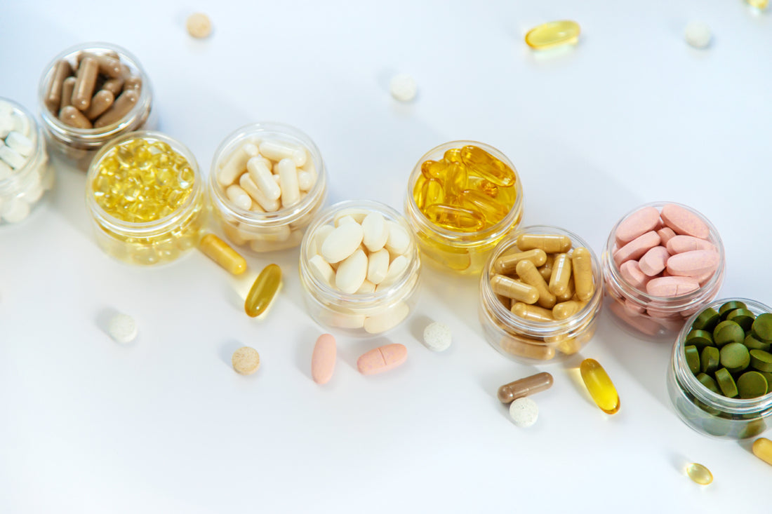 Ten small, clear plastic containers each holding a different type of vitamin or supplement.
