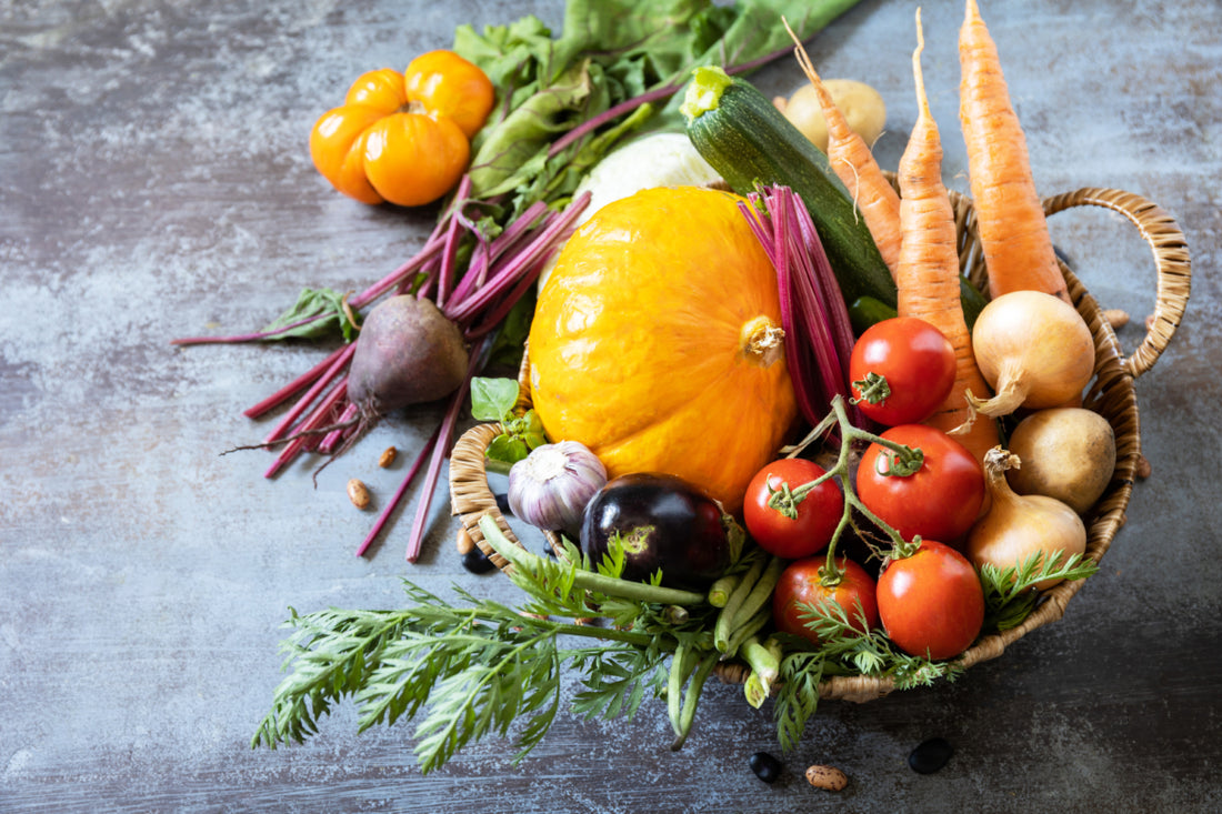 Wicker basket filled with fresh fruits and vegetables sitting on a dark stone counter.