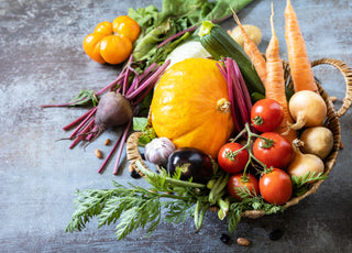 Wicker basket filled with fresh fruits and vegetables sitting on a dark stone counter.