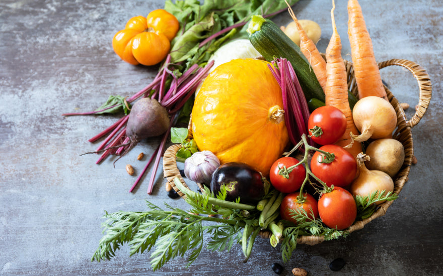 Wicker basket filled with fresh fruits and vegetables sitting on a dark stone counter.